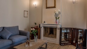 A living room with a fireplace, a sofa, a coffee table, and a cabinet with glassware. - Kyria House (Athens)