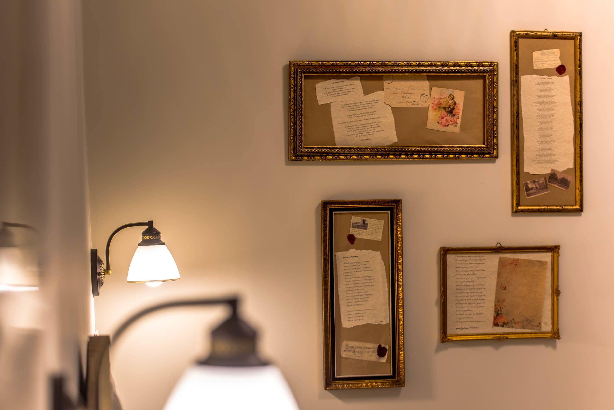 A wall with several framed documents and a wall-mounted lamp.
