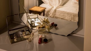 A bedroom with a large mirror reflecting a bed, a nightstand, and a hanging light fixture. - Kyria House (Athens)