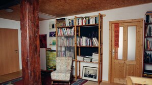 Una stanza accogliente con una libreria in legno, una poltrona a fantasia e un quadro appeso al muro.