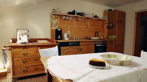 Una cucina con mobili in legno, una macchina per il caffè, un lavello e un tavolo con una torta e una ciotola.
