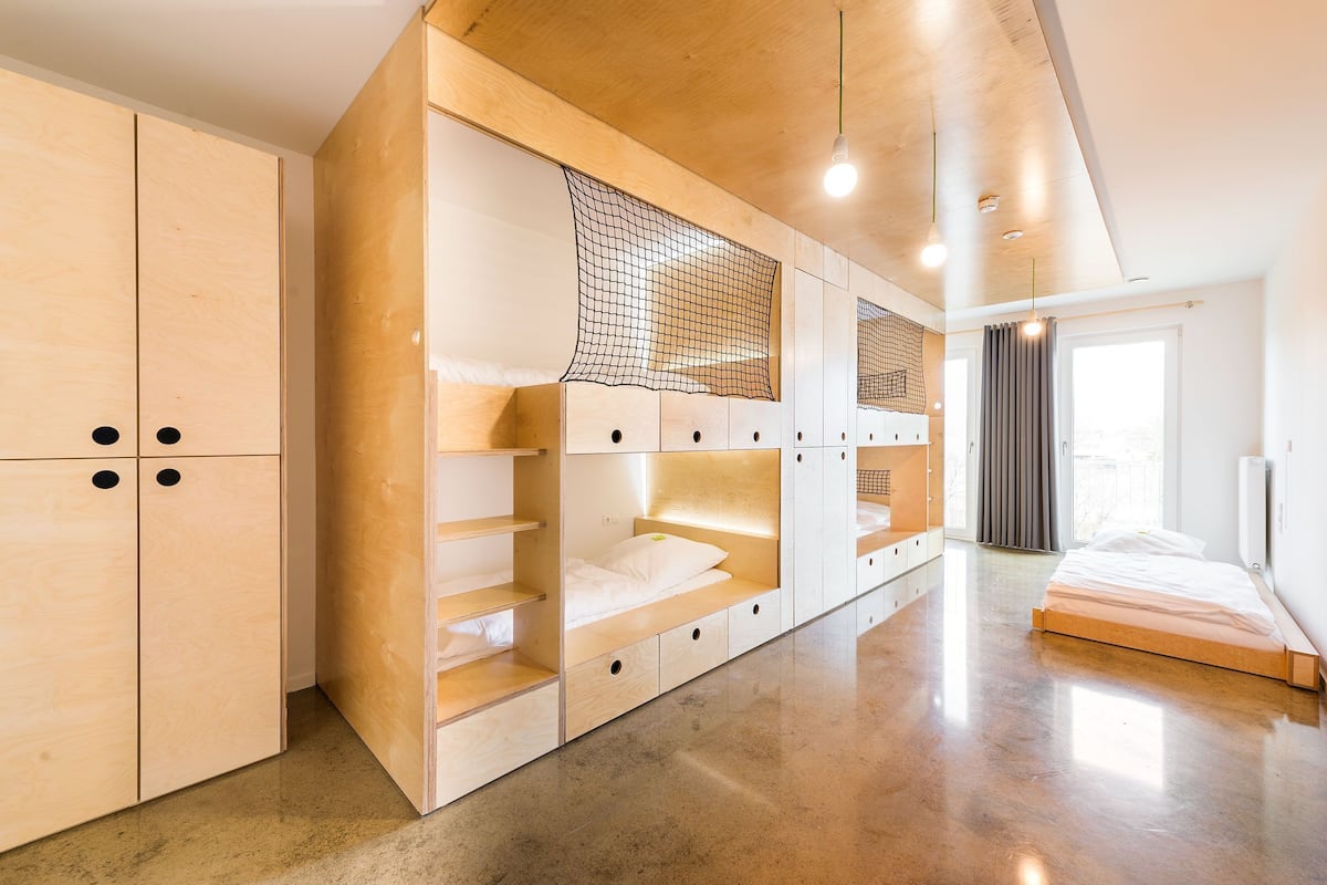 Un dormitorio moderno con almacenamiento de madera integrado, una cama y un amplio ventanal.
