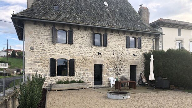 A stone building with multiple windows and a gravel courtyard.