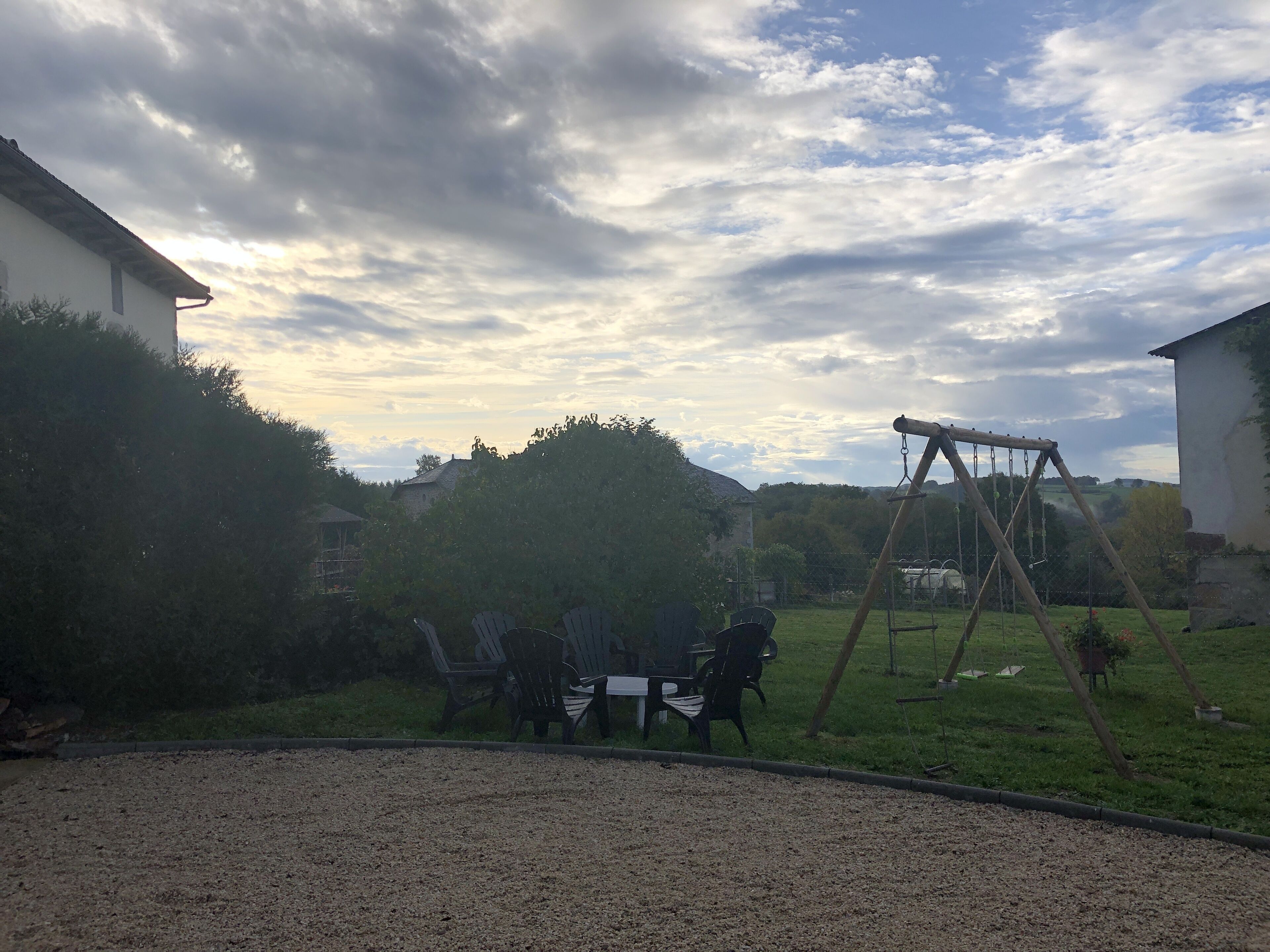 Un pati amb una taula i cadires, un parc infantil i una zona enjardinada.