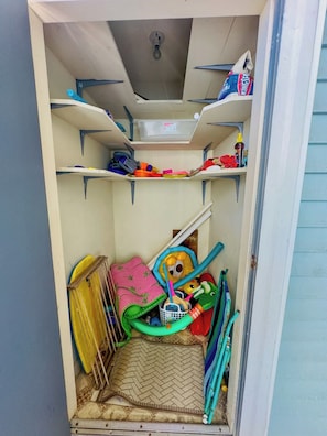 A storage space with shelves containing various items, a ceiling vent, and a small window.