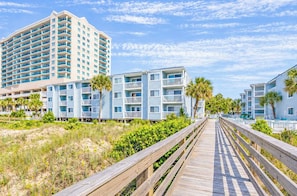 A coastal hotel with multiple-story buildings, a wooden boardwalk, and palm trees. - Ocean Garden Villas L2 (North Myrtle Beach)