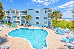 A hotel with a pool, multiple balconies, and a beach view.