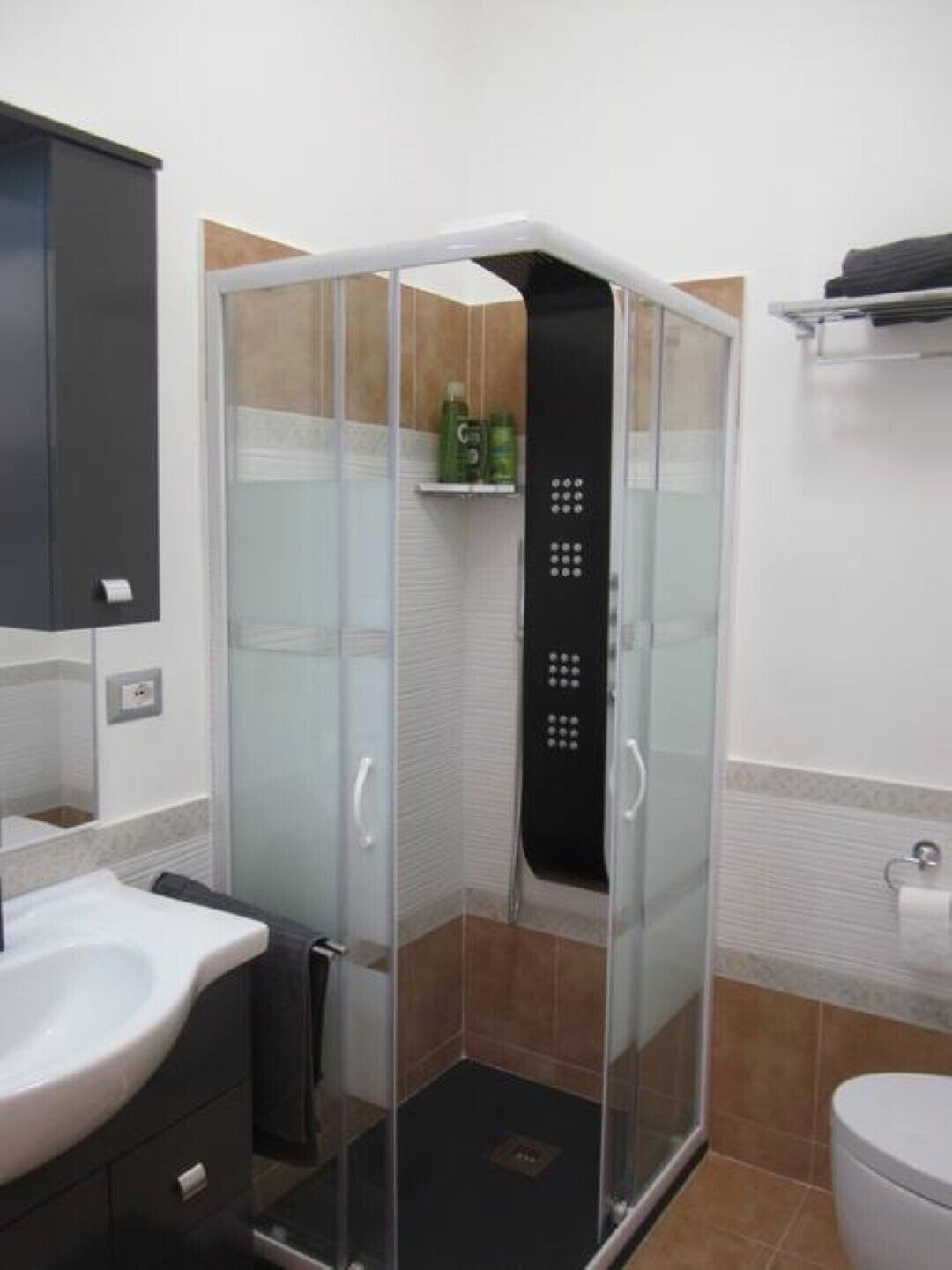 Un baño con ducha de vidrio, lavamanos e inodoro.