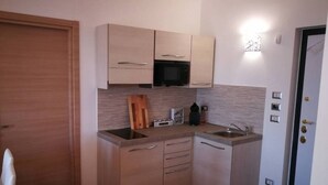 Une cuisine de taille réduite, équipée d’un four à micro-ondes, de deux éviers et d’un petit plan de travail.