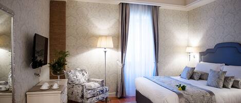 A hotel room with a bed, a chair, a desk, a lamp, and a window with curtains.