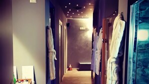 Un pasillo de hotel con suelo de madera, varios ganchos para albornoces y un banco en el centro.