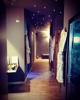 Un pasillo de hotel con suelo de madera, varios ganchos para albornoces y un banco en el centro.