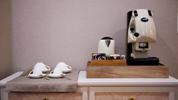 A coffee machine on a wooden tray with a coffee pot and cups on a table.