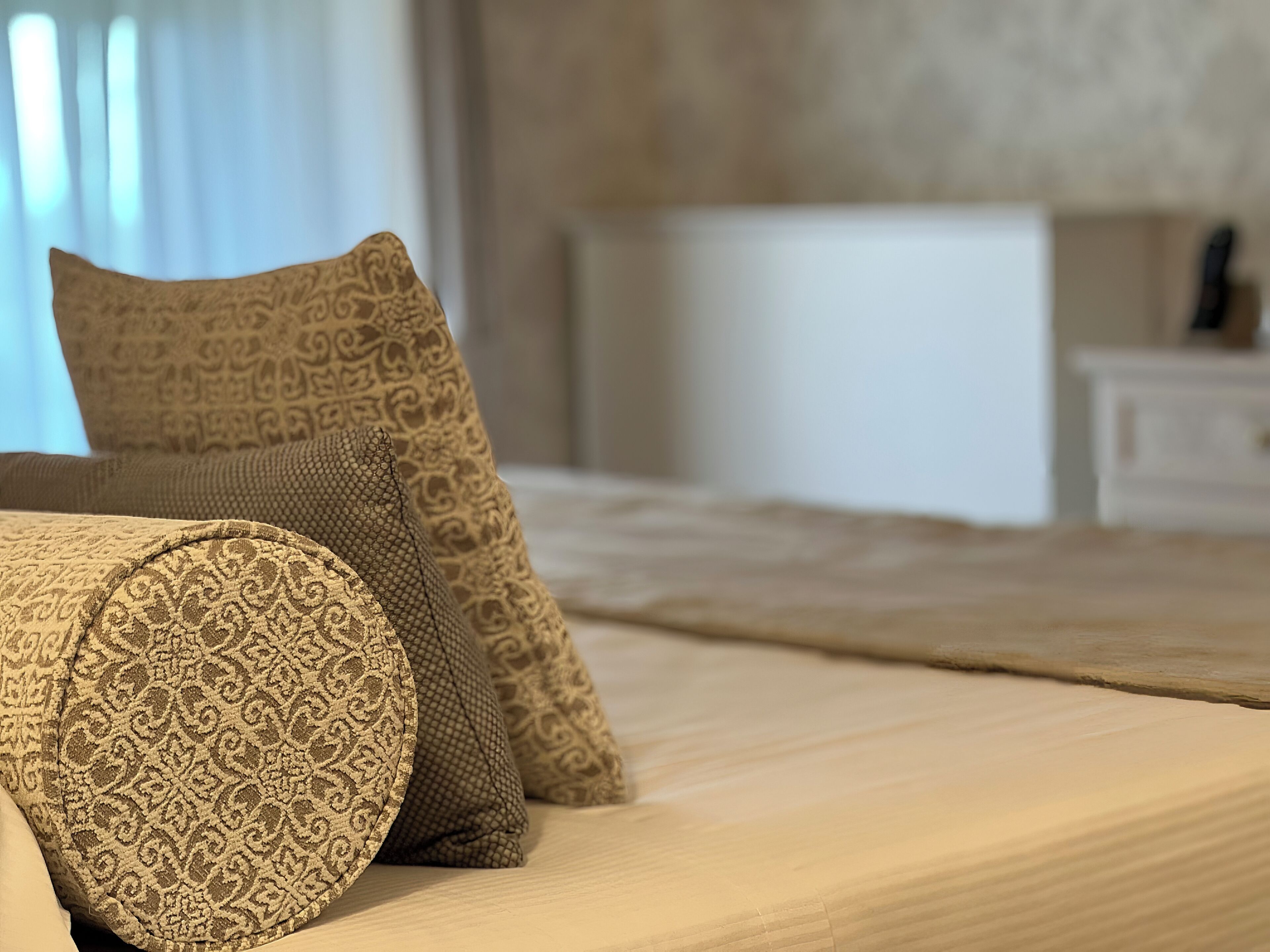 Una cama con una colcha estampada y almohadones decorativos.