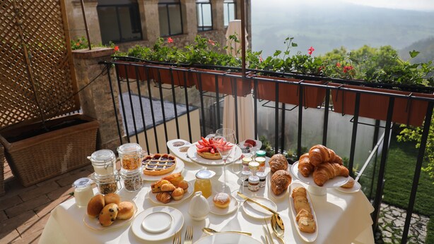 Una mesa dispuesta con alimentos para el desayuno en un balcón con vistas panorámicas.