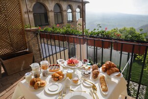 Una mesa dispuesta con alimentos para el desayuno en un balcón con vistas panorámicas.