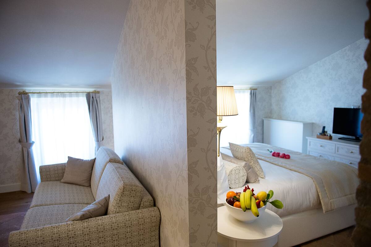 Une chambre d’hôtel avec un canapé, un lit agrémenté d’un panier de fruits, une lampe et un téléviseur.