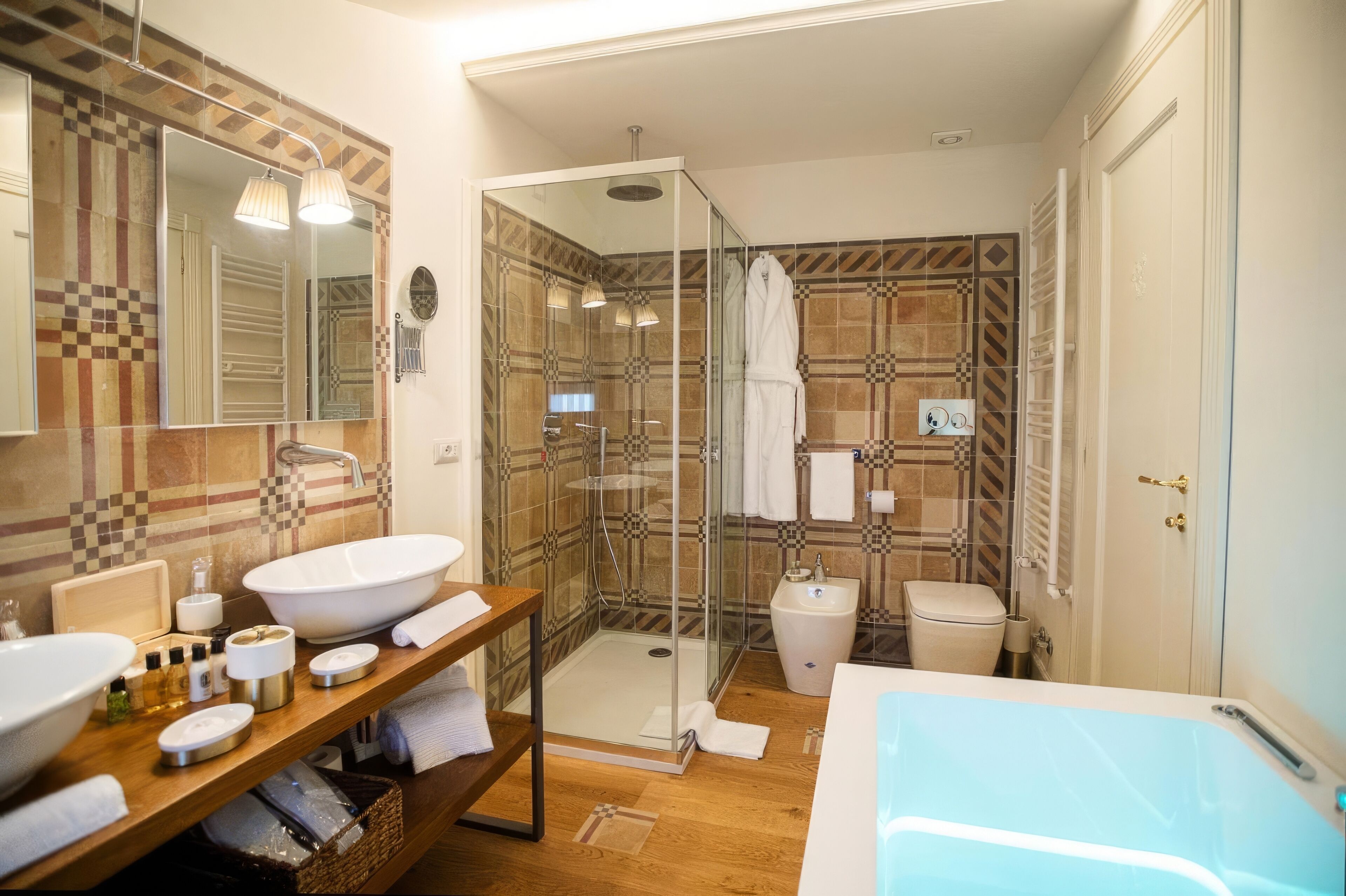 A modern bathroom with a glass-enclosed shower, a large bathtub, and a vanity with two sinks.