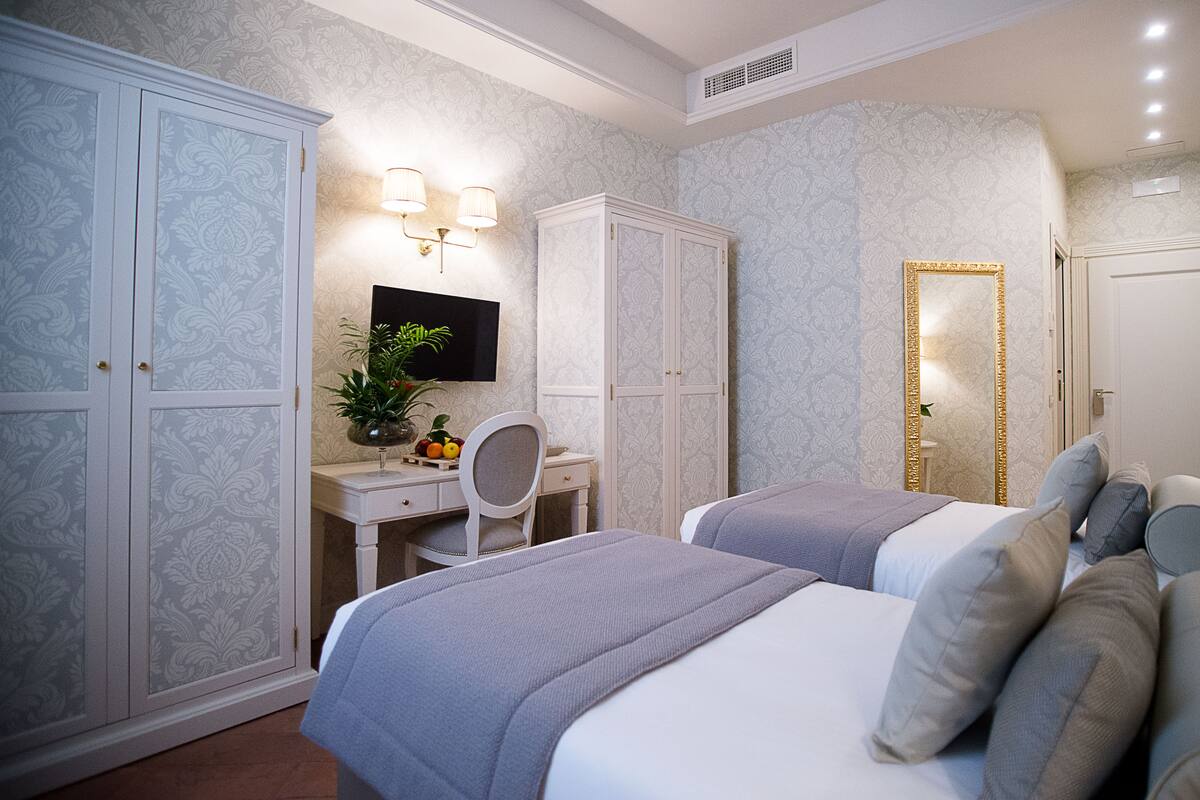 Une chambre avec deux lits, un bureau, une chaise et une télévision.