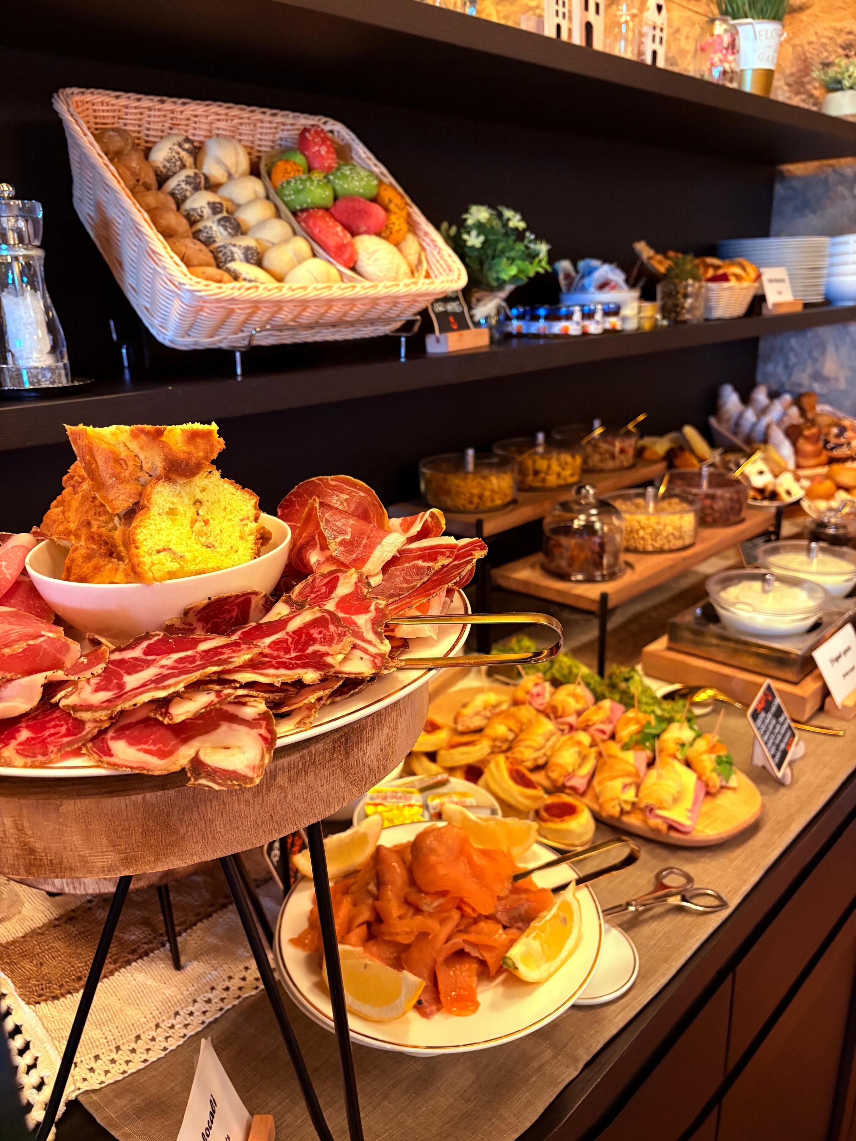 Un bufé con diversos alimentos, incluyendo pan, carnes y pasteles.