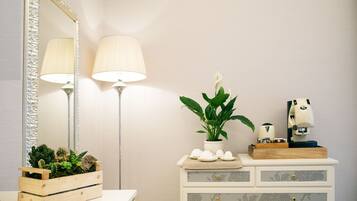 A bathroom with a mirror, two lamps, a potted plant, a coffee machine, and a wooden box with plants.