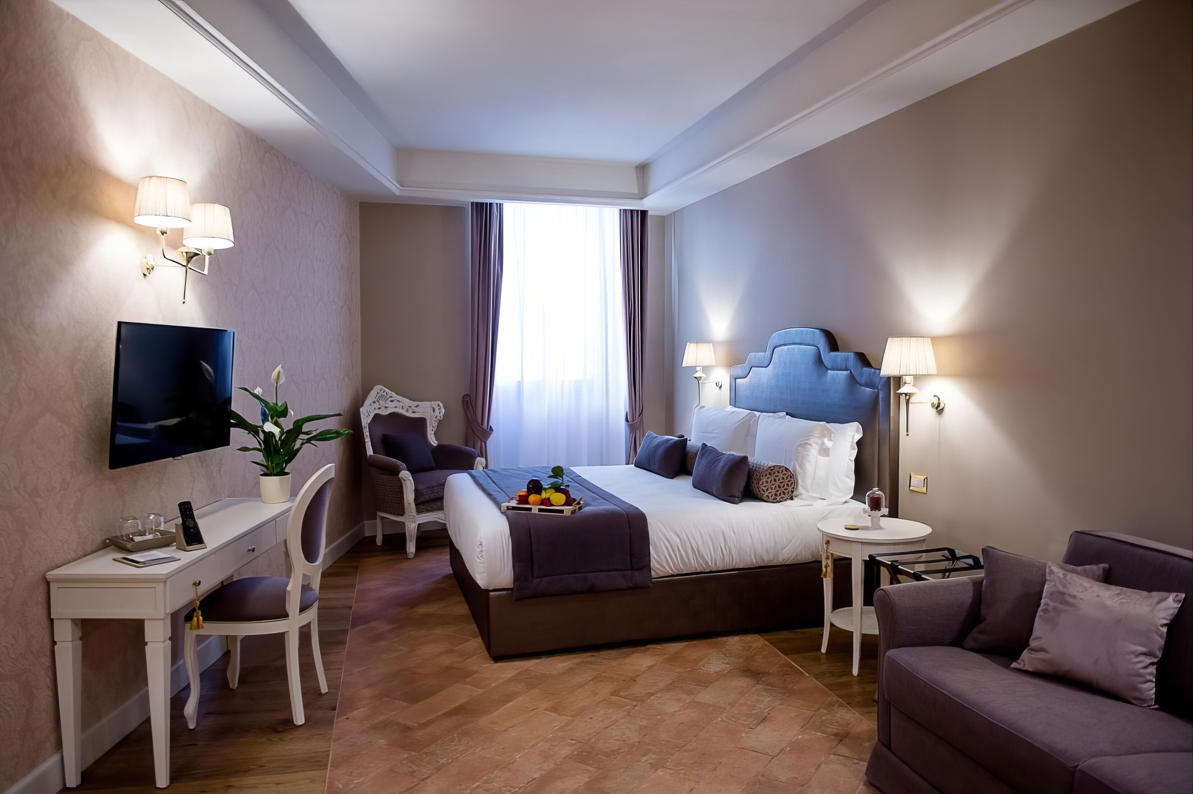 Une chambre d’hôtel moderne équipée d’un grand lit, d’un bureau, d’une chaise, d’un canapé et d’une télévision.