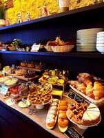 Un bufé con diversas opciones de comida, incluyendo pasteles, postres y una variedad de platos.