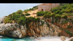 A coastal landscape with a beach, rocky cliffs, and a building. - B&B Baglio Cusenza (San Vito Lo Capo)