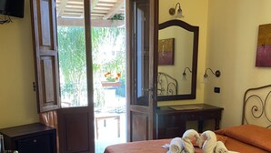 A bedroom with a bed, a bedside table, a wardrobe, a television, and a door leading to an outdoor area. - B&B Baglio Cusenza (San Vito Lo Capo)