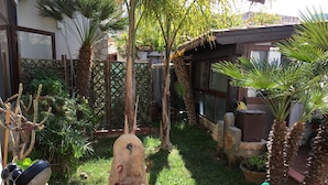 A garden with a stone fountain, potted plants, and a grill area. - B&B Baglio Cusenza (San Vito Lo Capo)