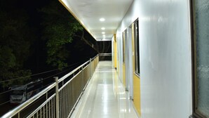 Un pasillo largo y bien iluminado, con barandilla de metal a un lado y ventanas al otro.