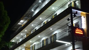 Un hotel de varios pisos con balcones, un restaurante y un letrero que dice 'Hotel Gananjaya'.