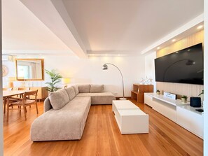 Un salon moderne avec un canapé d’angle, un téléviseur à écran plat et un coin repas doté de meubles en bois.