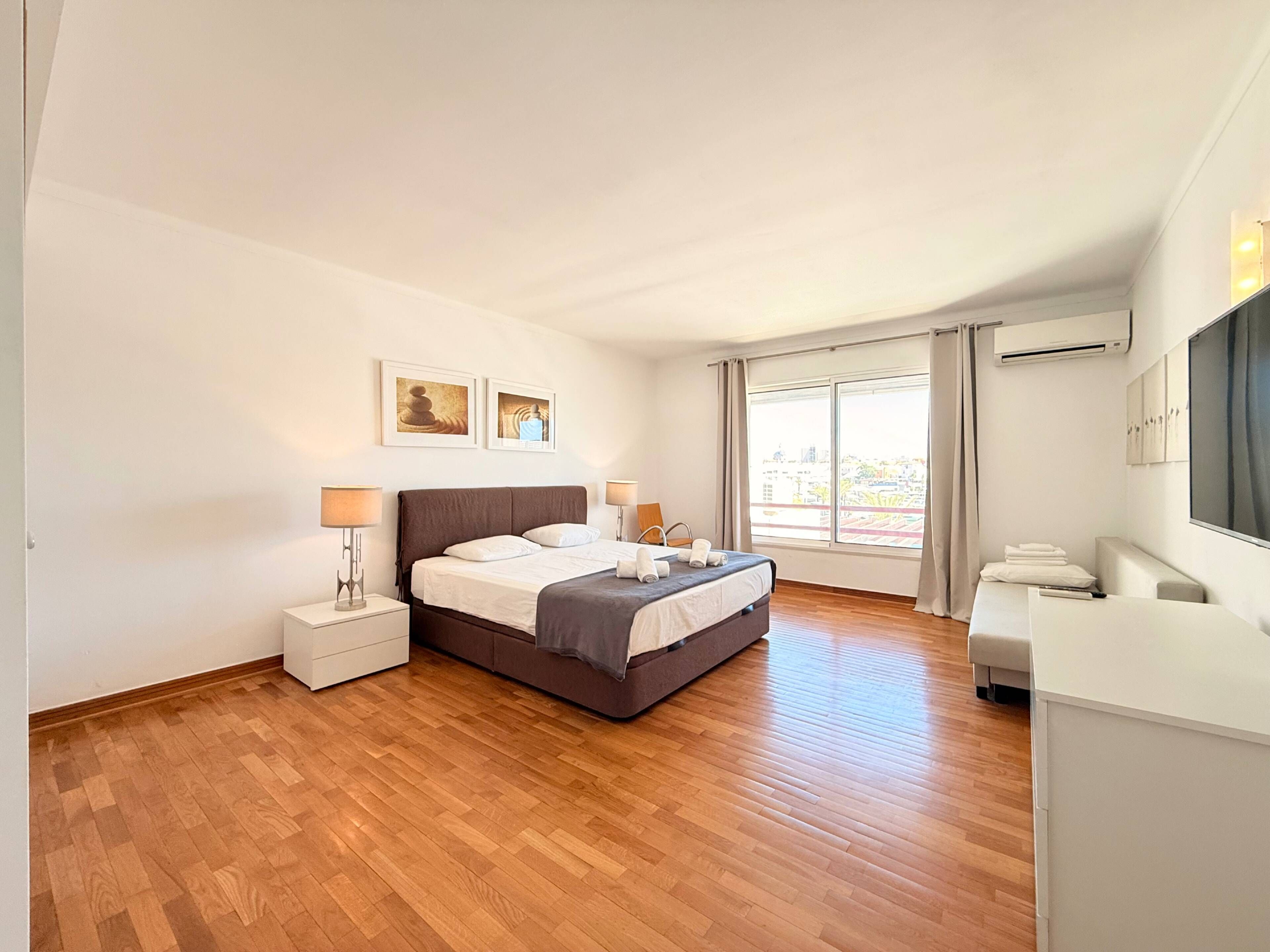 Een hotelkamer met een bed, nachtkastjes, een bureau en een groot raam.