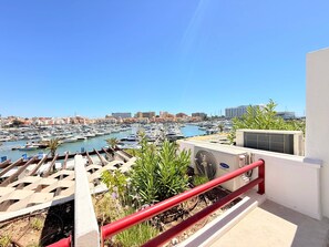 Un puerto deportivo con numerosas embarcaciones amarradas, cielo despejado y edificios al fondo.