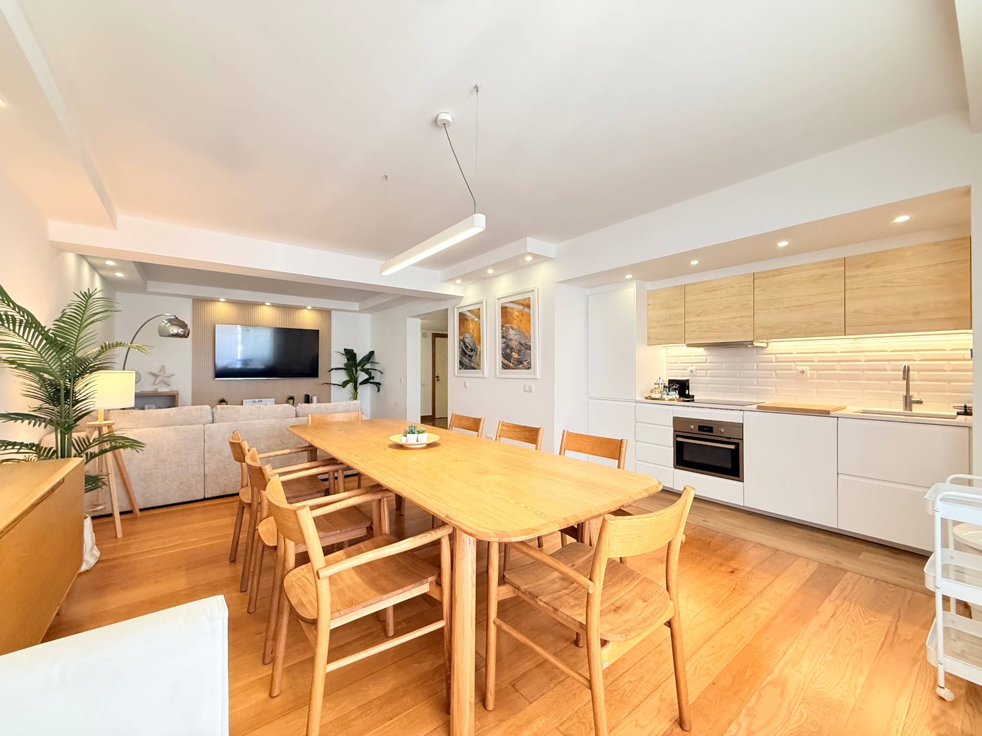 Een moderne keuken met witte kasten, een houten aanrechtblad en een ingebouwde oven.