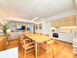 Una cocina moderna con armarios blancos, encimera de madera y horno empotrado.