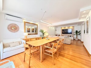 Un espacio habitable moderno con comedor, sofá y televisor montado en la pared.