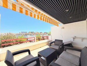 Un balcon avec des meubles d’extérieur, une vue sur la ville et une rambarde rouge.
