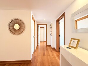Un pasillo con piso de madera, un espejo con diseño de sol y un certificado enmarcado sobre un mostrador.