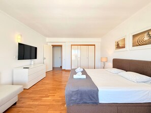 Une chambre d’hôtel comprenant un lit, une télévision, une commode et une porte donnant sur une autre pièce.