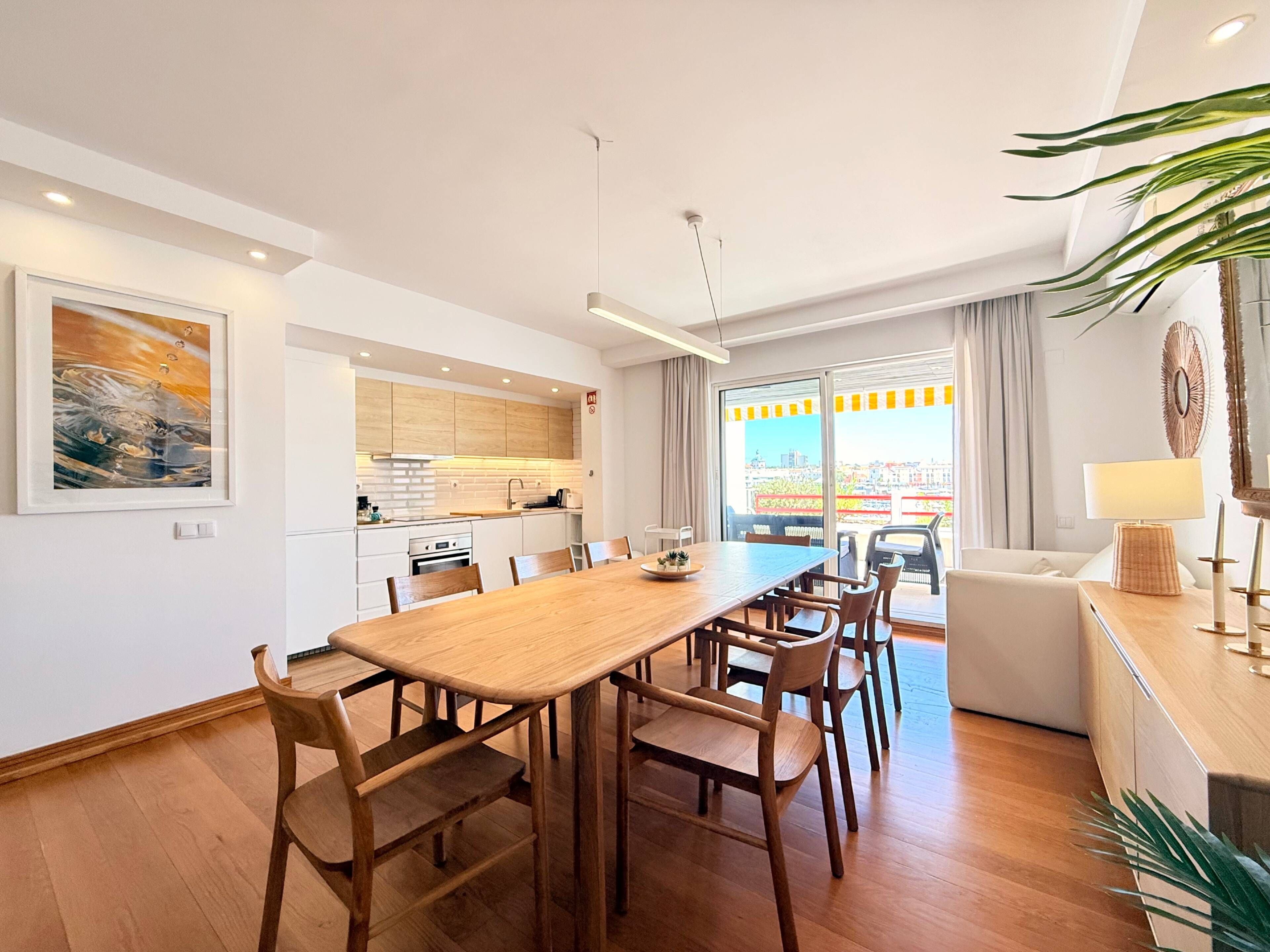 Un appartement moderne comprenant un coin repas, une cuisine et un balcon avec vue sur la ville.
