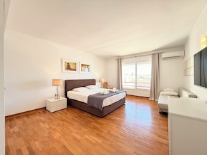Une chambre à coucher avec un lit, des tables de chevet, un bureau et une fenêtre avec des rideaux.