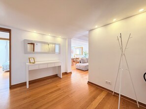 Un salon moderne avec une console blanche, un grand miroir et un plancher en bois.