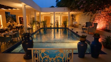 Una piscina al aire libre, sombrillas, sillones reclinables de piscina