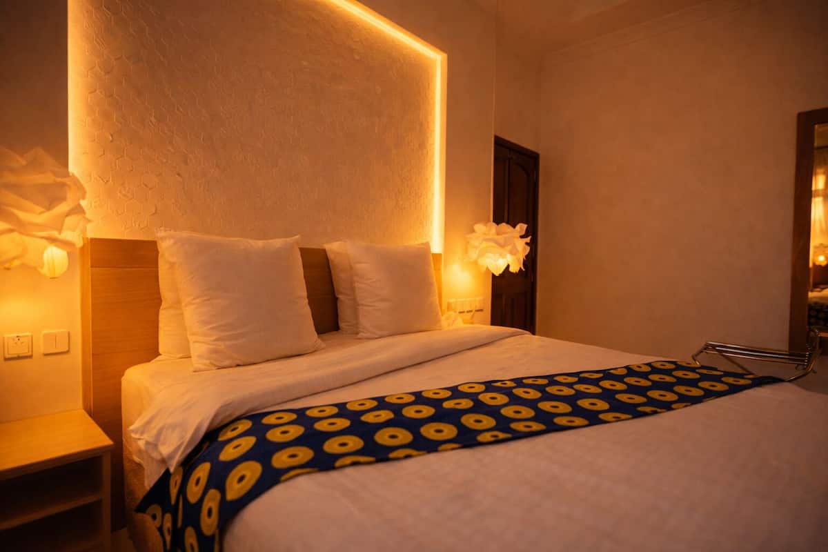 Ein Hotelzimmer mit einem Bett, einem Nachttisch, einer Lampe und einem Spiegel.