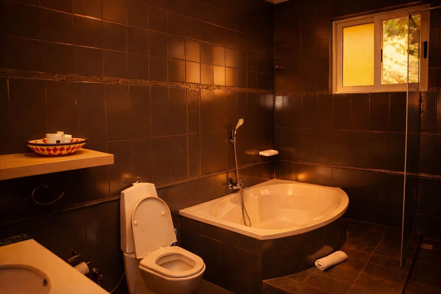 A bathroom with a bathtub, toilet, and a window with a view.