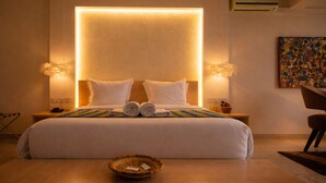 Une chambre d’hôtel avec un grand lit, deux lampes de chevet, une table de chevet avec un téléphone, un panier et un tableau au mur.