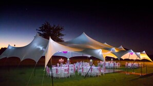 A tented outdoor event space with tables set up for dining.