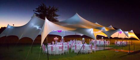 A tented outdoor event space with tables set up for dining.